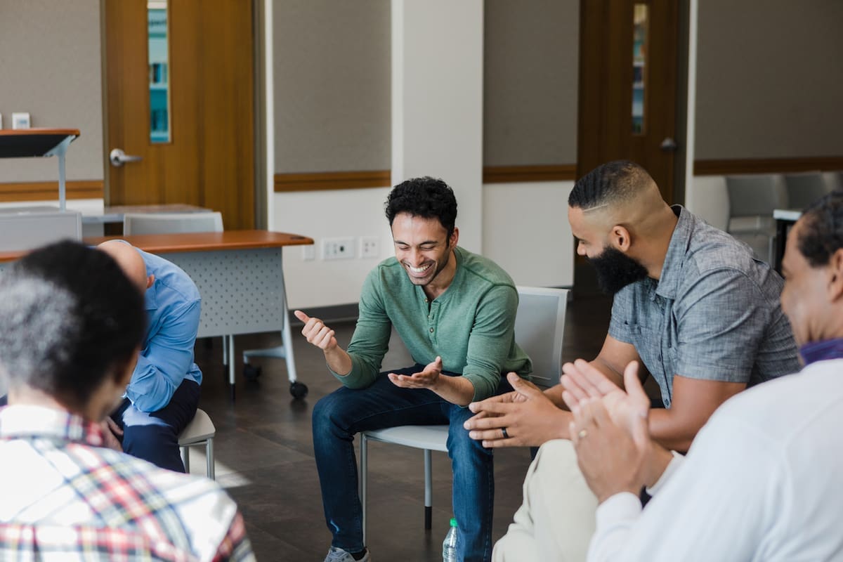 A group of people sitting in a circle laughing and listening to shared stories.