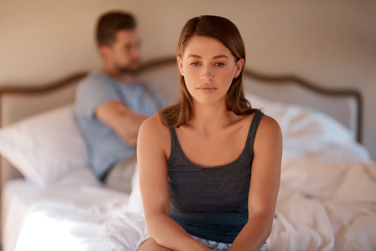 Sad, upset and couple in an argument in a bedroom. Toxic, mad and face of a woman fighting and in conflict with a man in her bed.