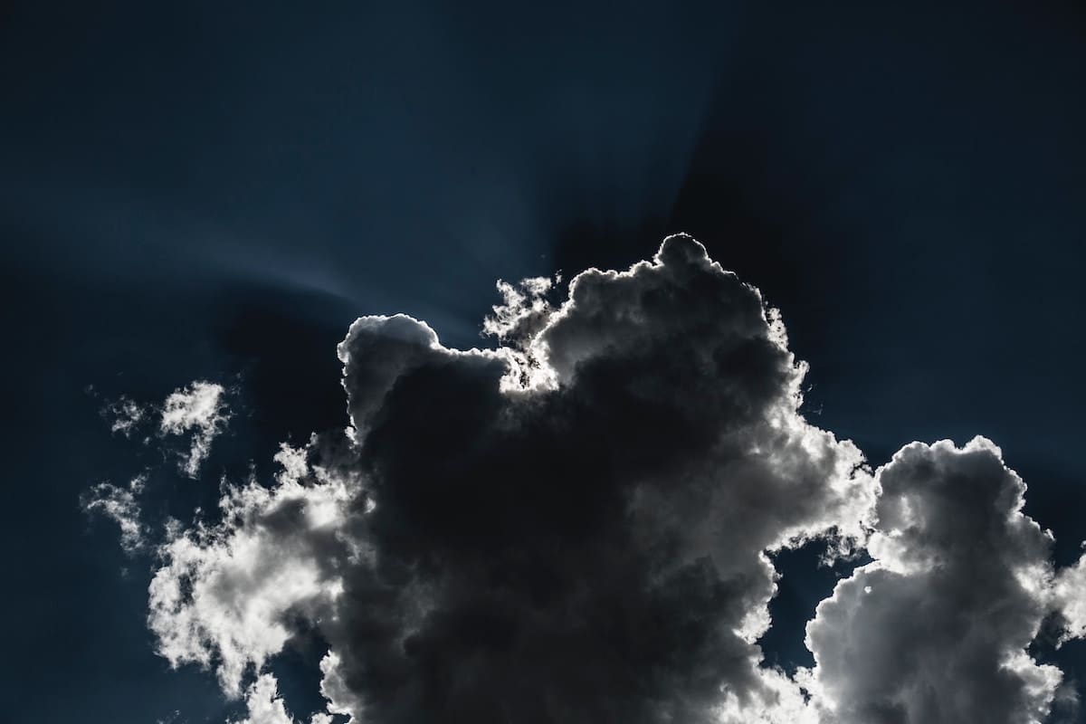 A dark sky with a very dark cloud with striking silver and white lining.