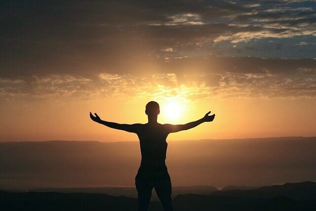 A woman with her arms spread open while looking at a sunrise. This image symbolizes being open to reading and growing from the following spiritual quotes.