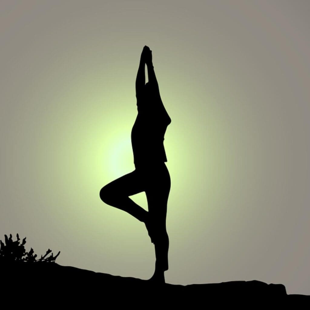 Figure silhouetted against sunlight doing mindfulness practice in the form of yoga