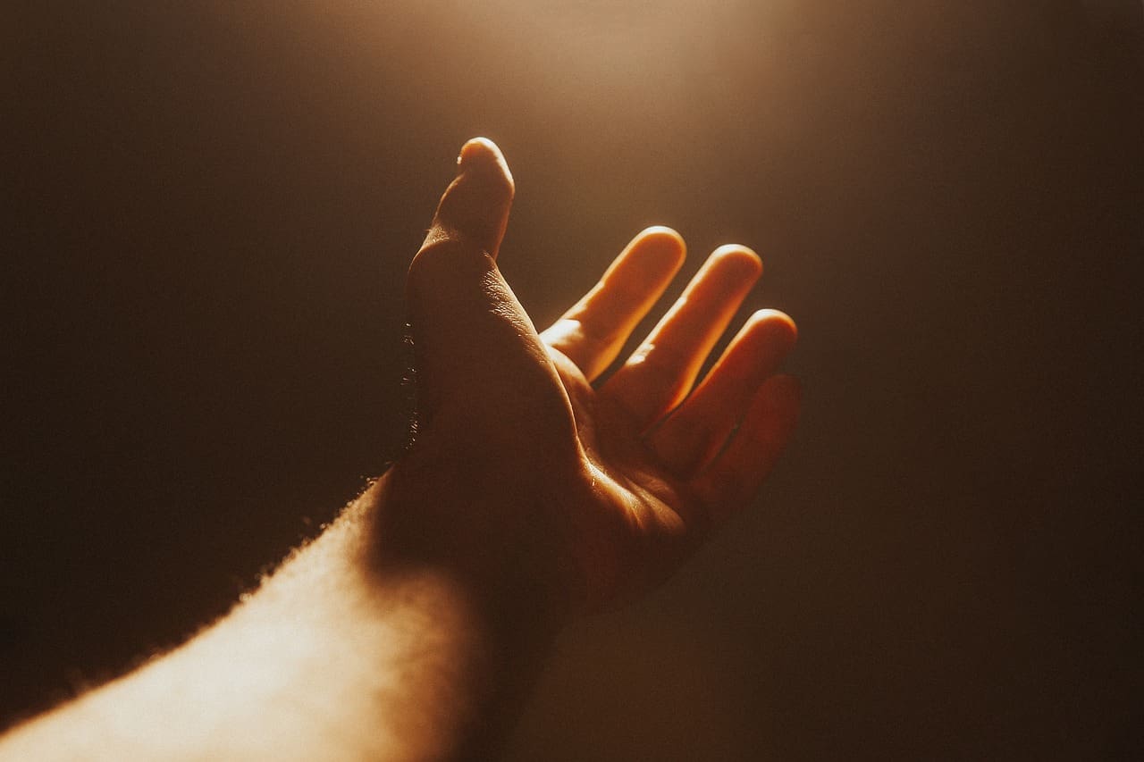 Image by 1857643 from Pixabay. Hand reaching out toward a light. 