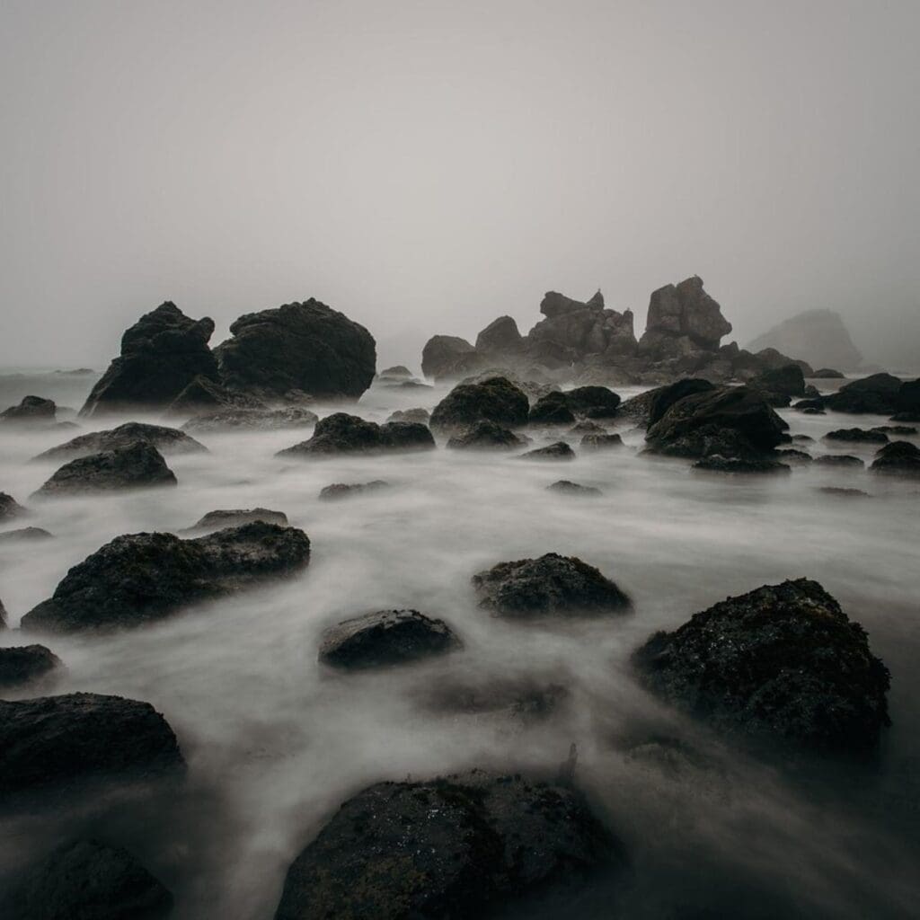 Rocks jutting out of the water on foggy, cloudy day. 