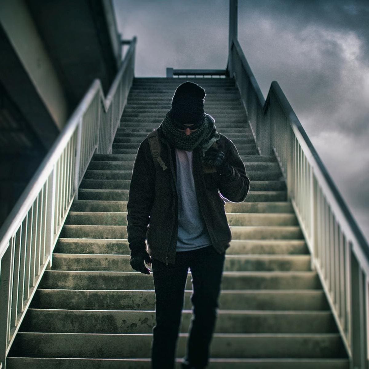 Image by StockSnap from Pixabay. Man in winter heat, scarf, jacket coming down train platform steps.