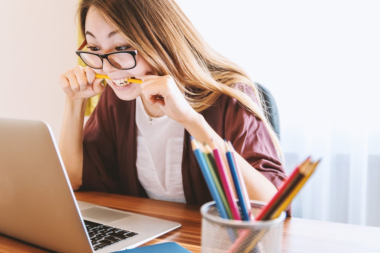 Woman in front of laptop biting a pencil in anticipation. Image by Jan Vašek from Pixabay