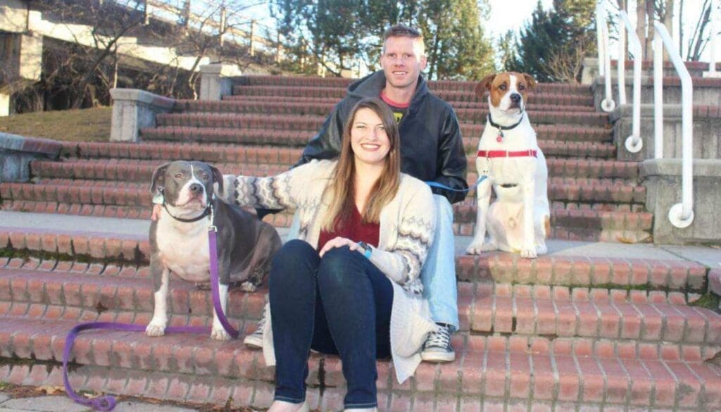 Tricia, Director of Finance and Personnel for UM-Missoula, sits on steps with her husband and two dogs. 