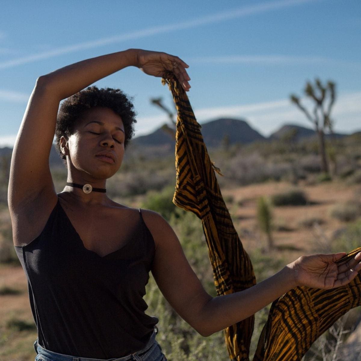 Black woman dancing in desert with scarf