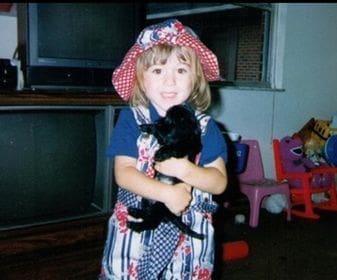 Kristin Oesterle as a young child, holding a black puppy