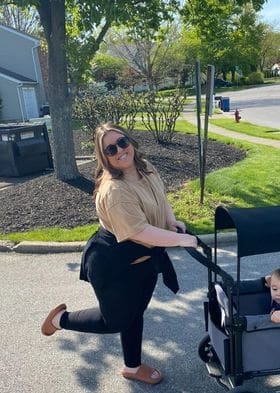 Kristin Oesterle as a grown woman and mother, pushing her sons in a stroller, looking happy. 