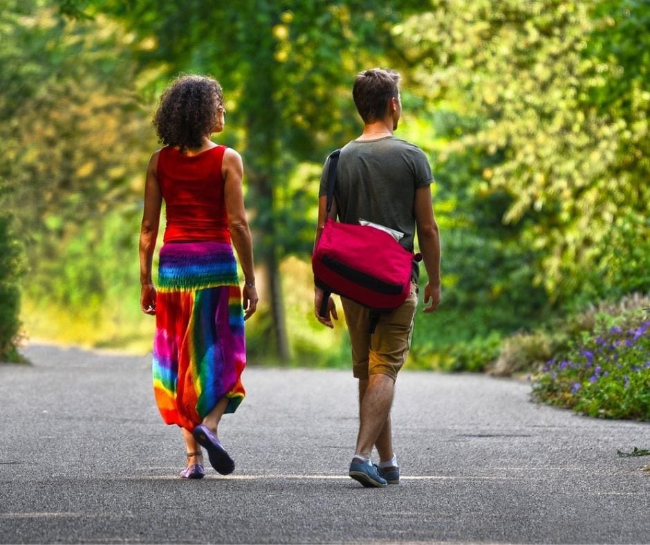 Couple walking along a park path, not touching each other. 