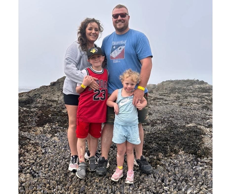 Photo of family by the ocean; mom, dad, son, and daughter.