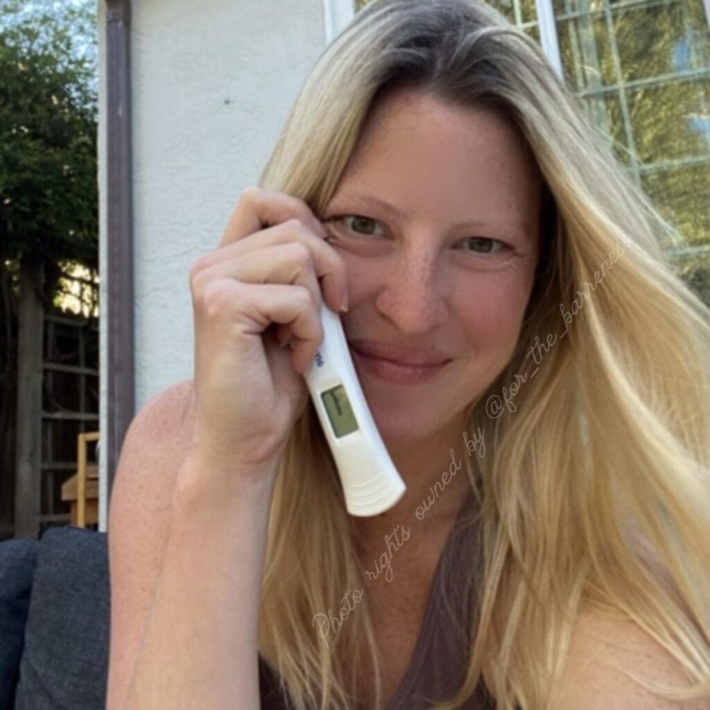 A photo of Meg Faith with a pregnancy test during her infertility journey.