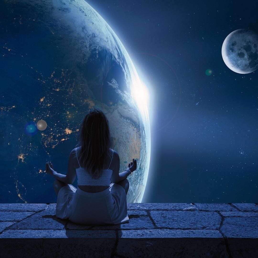 Woman sitting on ledge in lotus position, meditating, with earth, the moon, and cosmos beyond her.