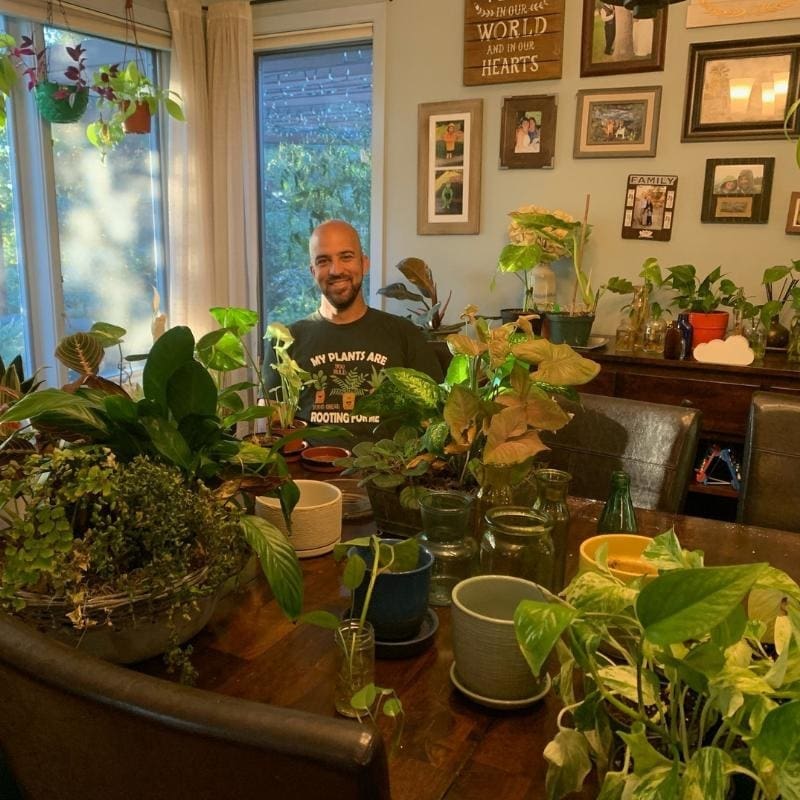 A photo of Nathan surrounded by his plants. These plants are part of his hobby and business he founded after his constructive dismissal/